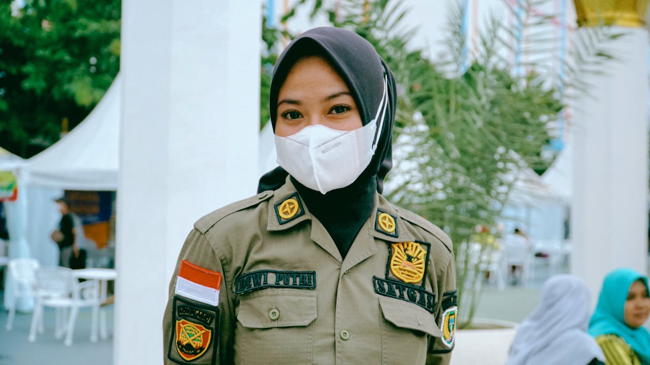 Woman in Indonesian Police Uniform, Headscarf, and Face Mask